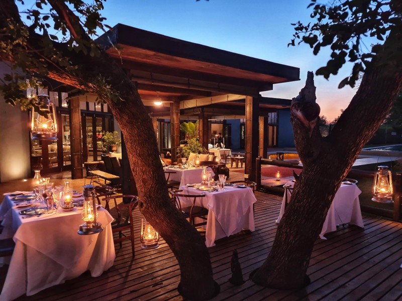 Upplyst restaurang i skymningen med dukade bord under bar himmel i Sydafrika.